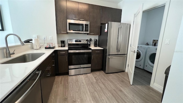 kitchen with sink, light wood-type flooring, dark brown cabinetry, stainless steel appliances, and washing machine and clothes dryer