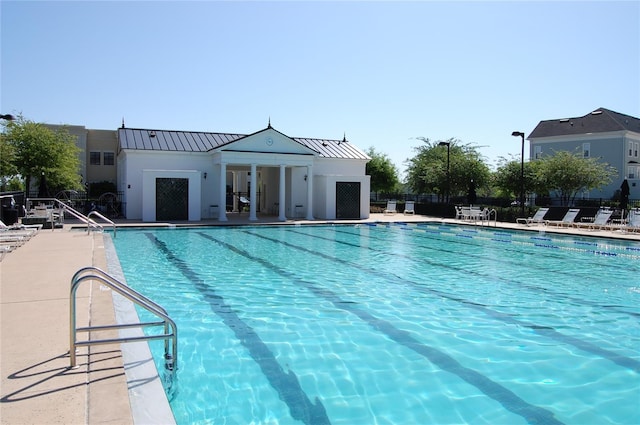 pool with a patio area, fence, and an outbuilding
