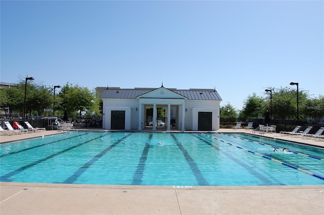 community pool featuring a patio area, fence, and an outdoor structure