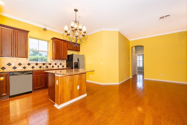 kitchen featuring tasteful backsplash, a center island, visible vents, stainless steel appliances, and arched walkways