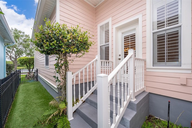 view of exterior entry featuring a yard and fence