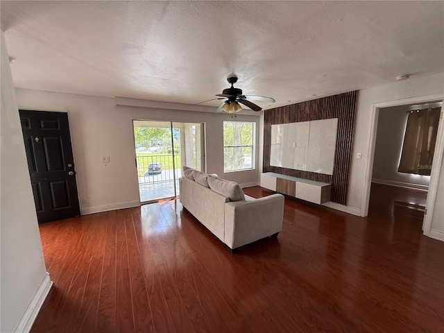 unfurnished living room with ceiling fan, dark hardwood / wood-style flooring, and a textured ceiling