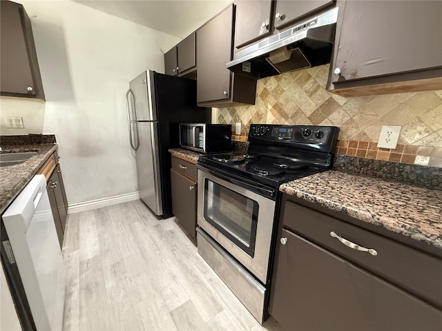 kitchen with dark stone countertops, light wood-type flooring, appliances with stainless steel finishes, and tasteful backsplash