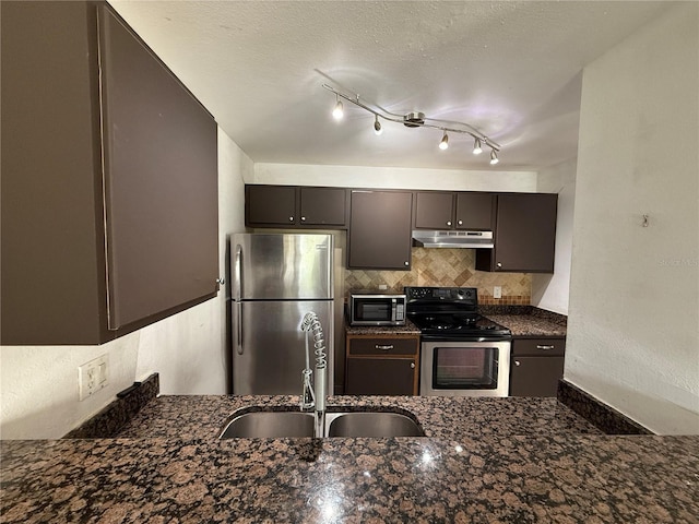 kitchen featuring dark brown cabinetry, sink, dark stone counters, decorative backsplash, and appliances with stainless steel finishes