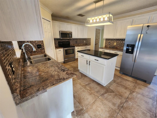 kitchen featuring appliances with stainless steel finishes, a kitchen island, decorative light fixtures, white cabinetry, and sink