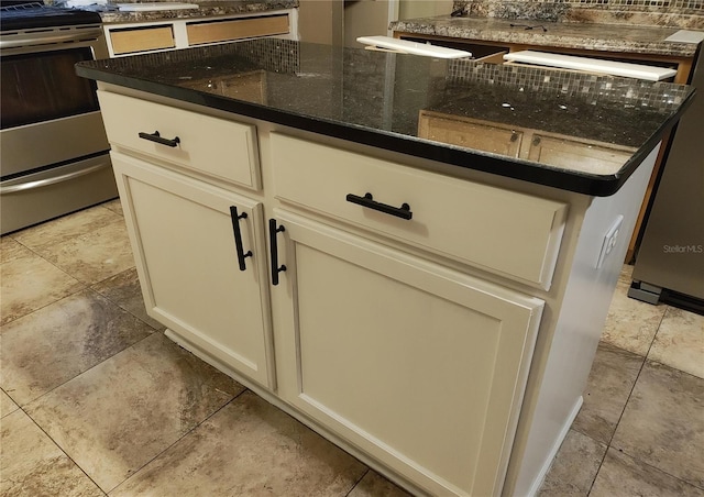 room details with cream cabinets, stainless steel electric range oven, and dark stone counters