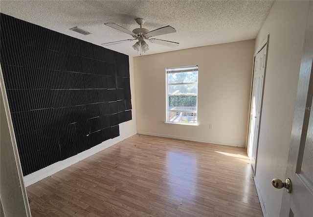 empty room featuring ceiling fan, wood-type flooring, and a textured ceiling