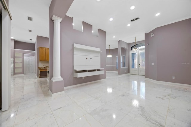 unfurnished living room with decorative columns, french doors, a high ceiling, and an inviting chandelier