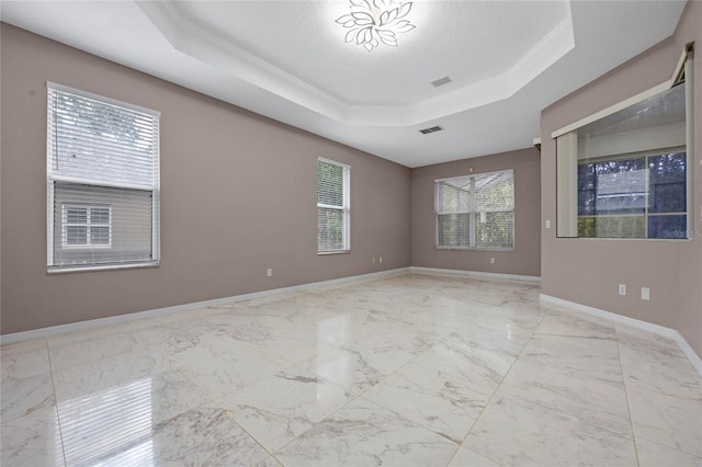 unfurnished room with a textured ceiling, a raised ceiling, a wealth of natural light, and crown molding