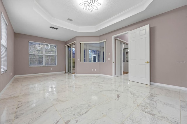 spare room featuring a textured ceiling, a raised ceiling, and ornamental molding