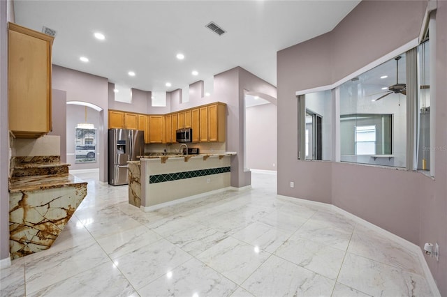 kitchen with kitchen peninsula, appliances with stainless steel finishes, a towering ceiling, ceiling fan, and sink