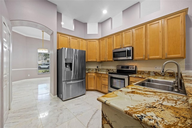 kitchen with light stone countertops, a towering ceiling, stainless steel appliances, sink, and hanging light fixtures