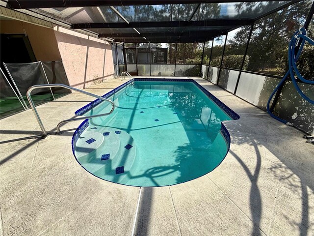 view of swimming pool with glass enclosure and a patio area