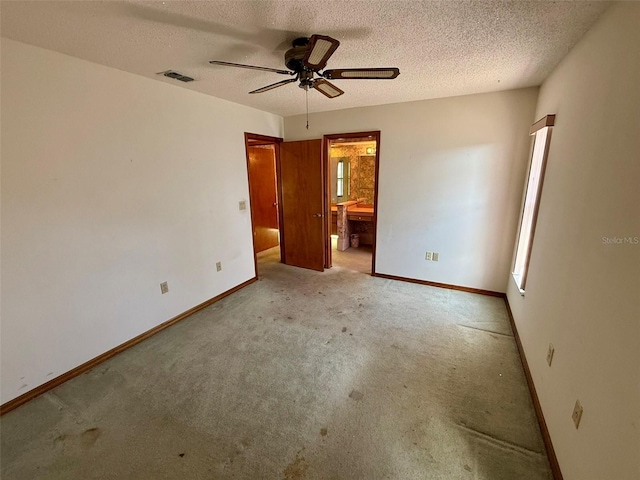 unfurnished bedroom with light carpet, a textured ceiling, ensuite bath, and ceiling fan