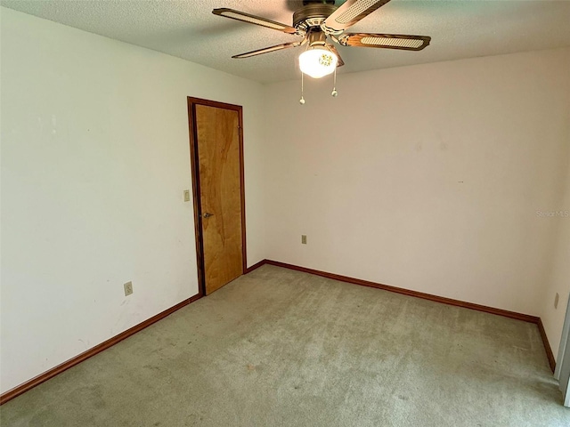 empty room with ceiling fan, light colored carpet, and a textured ceiling