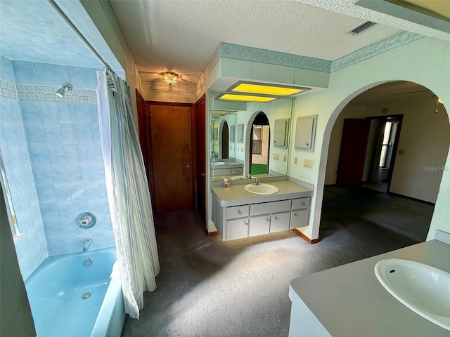 bathroom with a textured ceiling, vanity, and shower / bath combo