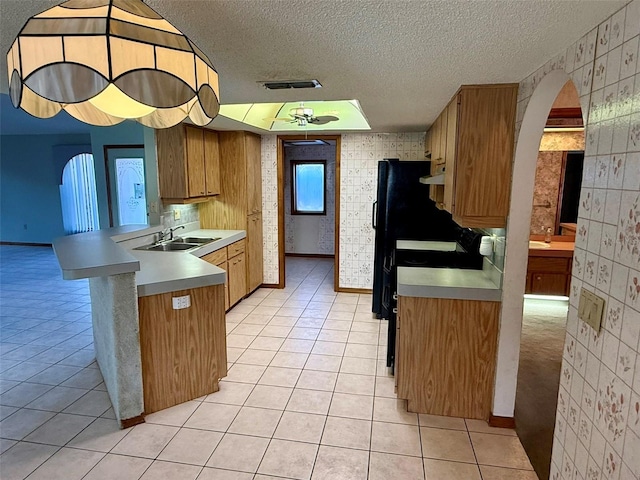 kitchen with sink, kitchen peninsula, a textured ceiling, a breakfast bar area, and light tile patterned floors