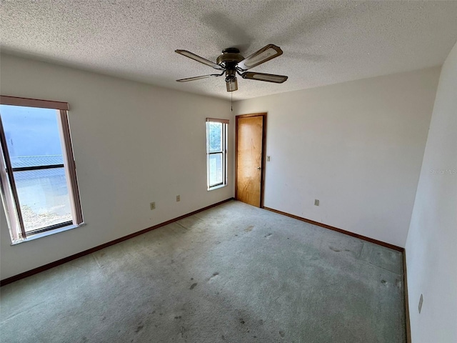 carpeted spare room with ceiling fan and a textured ceiling