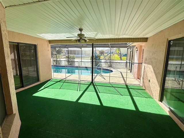 unfurnished sunroom featuring ceiling fan and a swimming pool