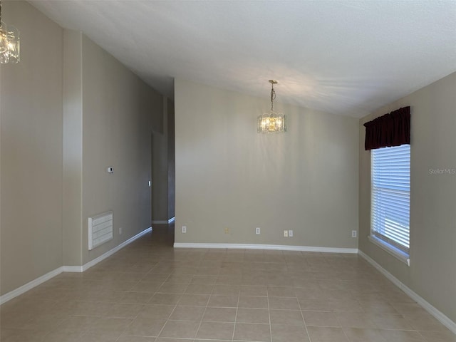 tiled empty room featuring vaulted ceiling and a chandelier