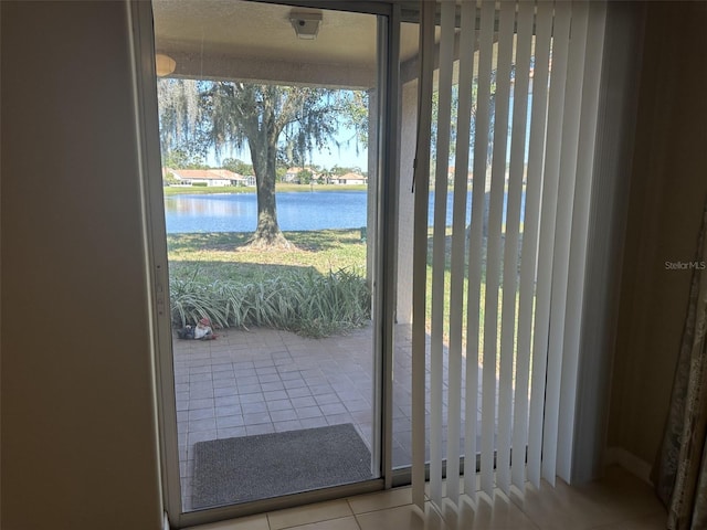 doorway with a water view and light tile patterned flooring