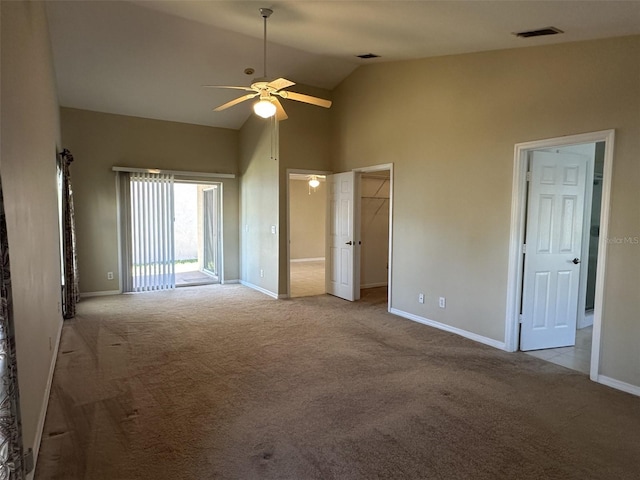 interior space featuring a walk in closet, ceiling fan, light colored carpet, and vaulted ceiling