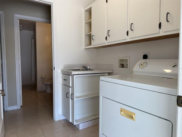 clothes washing area with washer / clothes dryer, sink, light tile patterned flooring, and cabinets