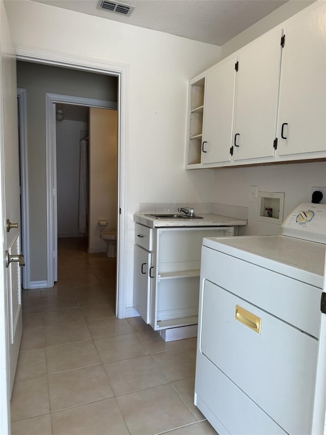 clothes washing area featuring cabinets, light tile patterned floors, washer / clothes dryer, and sink