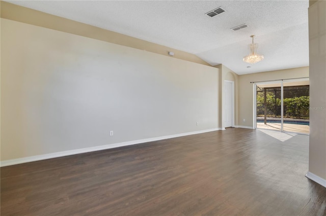 spare room with a textured ceiling, lofted ceiling, dark wood-type flooring, and an inviting chandelier