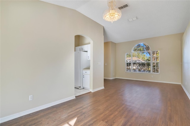 unfurnished room featuring light wood-type flooring, lofted ceiling, and an inviting chandelier