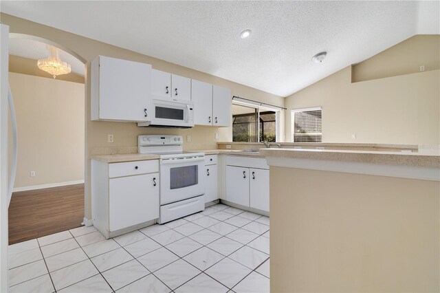 kitchen with white cabinetry, vaulted ceiling, a textured ceiling, white appliances, and light tile patterned floors