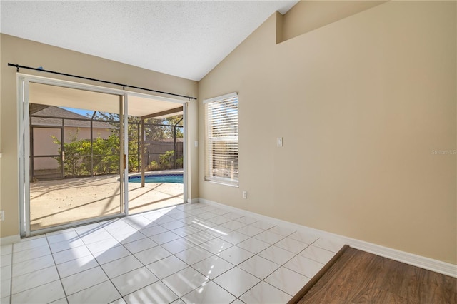 spare room featuring a textured ceiling, vaulted ceiling, and light tile patterned flooring