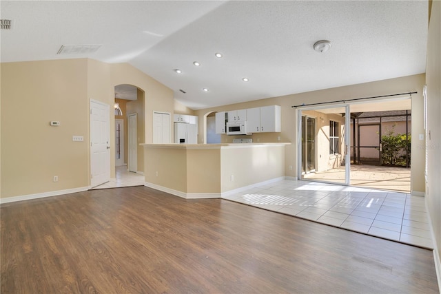 unfurnished living room with light wood-type flooring and vaulted ceiling