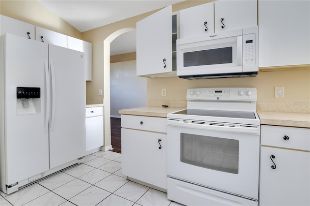 kitchen featuring vaulted ceiling, light tile patterned floors, white cabinets, and white appliances