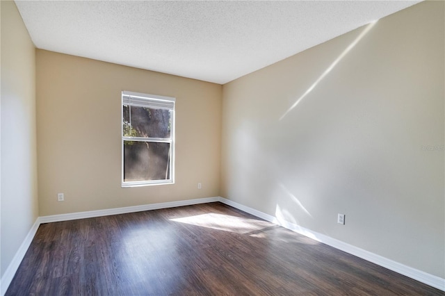 empty room with a textured ceiling and dark hardwood / wood-style flooring