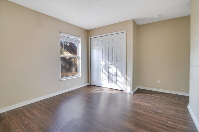 spare room featuring a textured ceiling and dark hardwood / wood-style floors