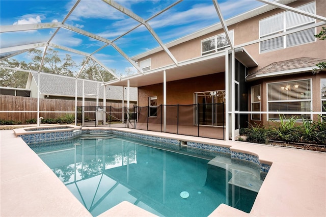 view of pool with glass enclosure, a patio area, and an in ground hot tub