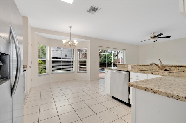 kitchen featuring pendant lighting, white cabinets, ceiling fan with notable chandelier, light tile patterned floors, and appliances with stainless steel finishes