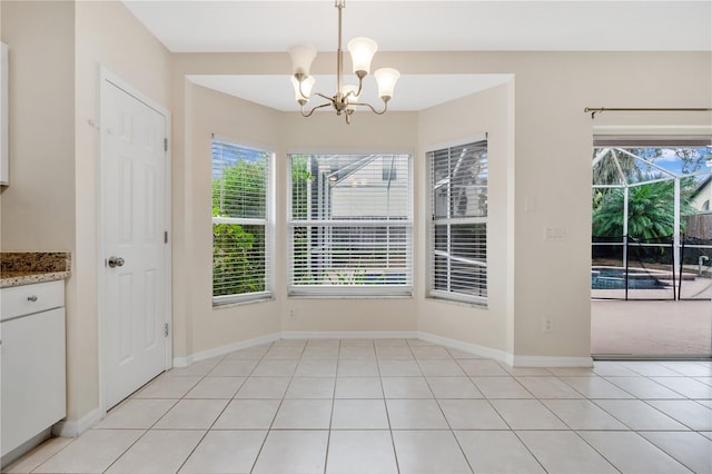 unfurnished dining area with plenty of natural light, light tile patterned floors, and a chandelier