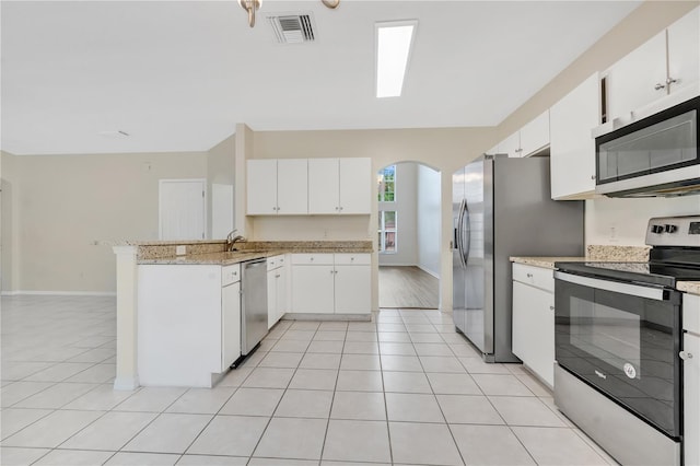 kitchen with kitchen peninsula, appliances with stainless steel finishes, white cabinets, and light tile patterned floors