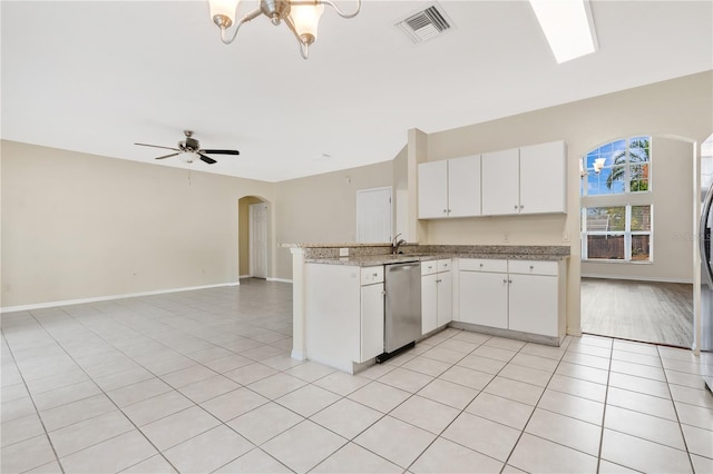 kitchen with ceiling fan with notable chandelier, kitchen peninsula, stainless steel dishwasher, light tile patterned floors, and white cabinetry