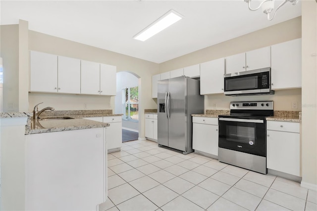 kitchen with sink, light stone counters, light tile patterned flooring, white cabinets, and appliances with stainless steel finishes