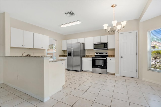 kitchen with kitchen peninsula, appliances with stainless steel finishes, decorative light fixtures, a chandelier, and white cabinetry