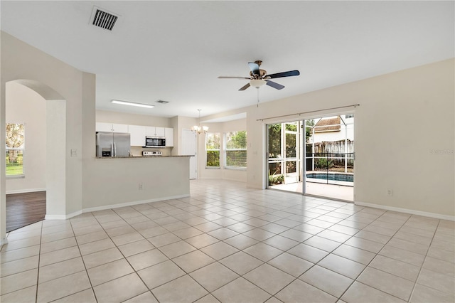 unfurnished living room with ceiling fan with notable chandelier and light tile patterned floors