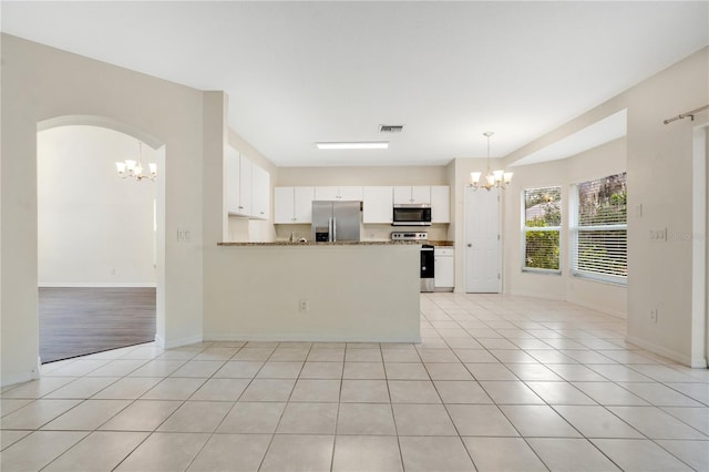 kitchen with kitchen peninsula, light stone countertops, light tile patterned floors, appliances with stainless steel finishes, and white cabinetry