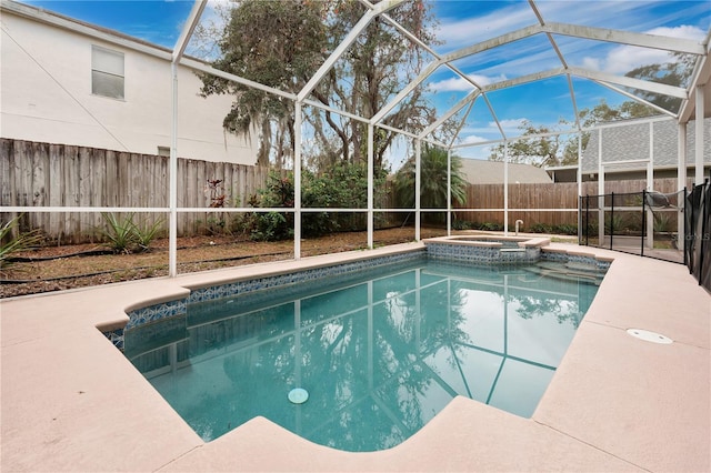 view of pool with glass enclosure, an in ground hot tub, and a patio