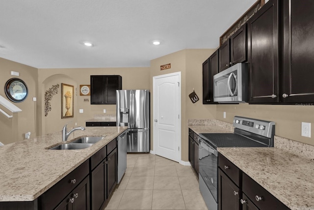 kitchen with sink, light stone counters, a center island with sink, light tile patterned floors, and appliances with stainless steel finishes