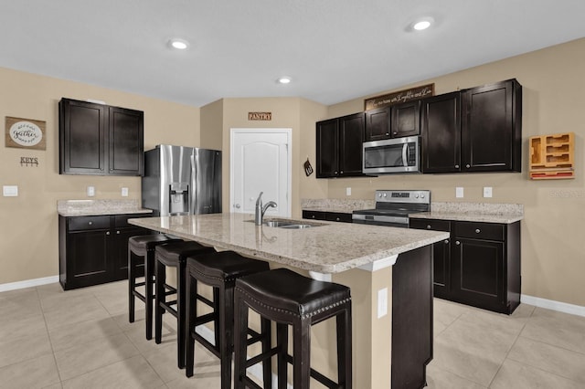 kitchen with stainless steel appliances, sink, a center island with sink, a breakfast bar area, and light tile patterned flooring