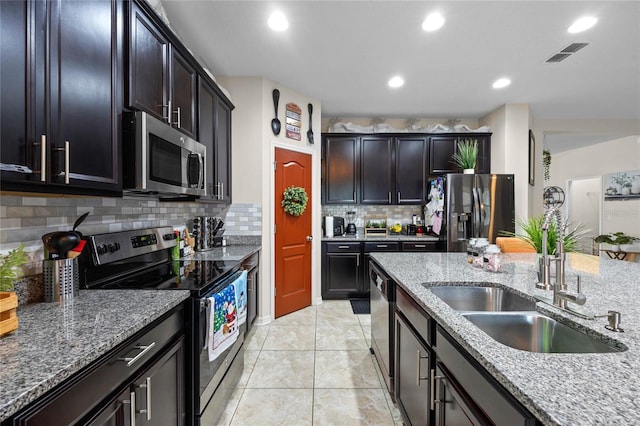 kitchen with decorative backsplash, appliances with stainless steel finishes, light stone counters, and sink