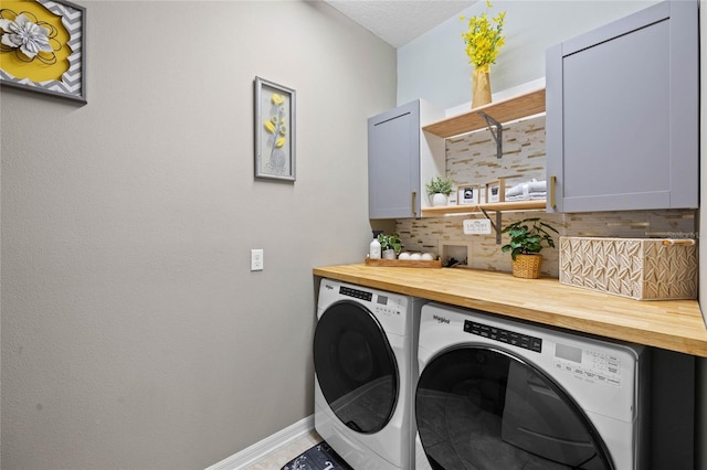 laundry room featuring cabinets, a textured ceiling, and separate washer and dryer